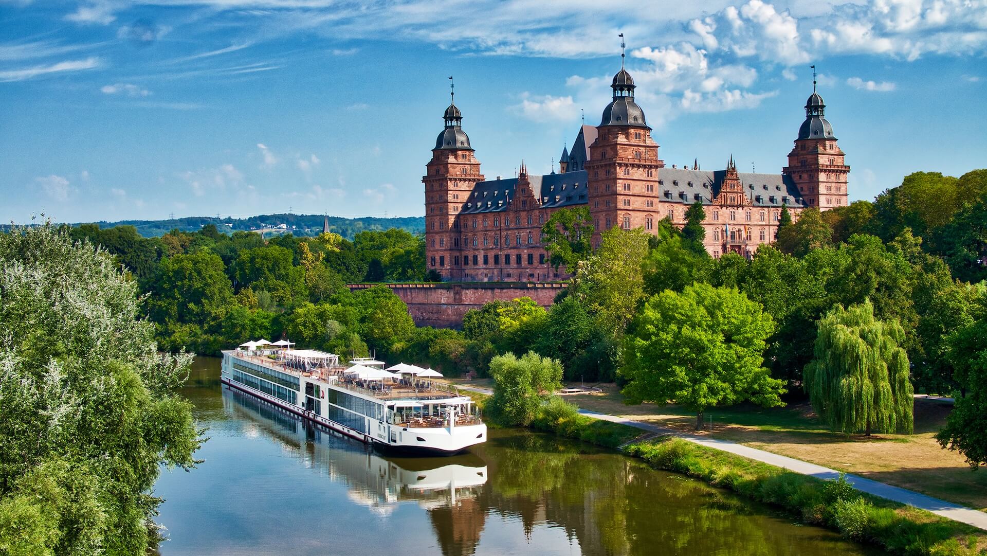 Cruise boat near historic castle on a river.