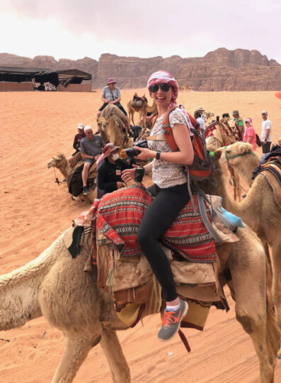 People riding camels in desert setting.