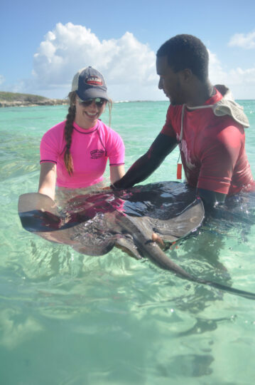 Two people holding a stingray in water